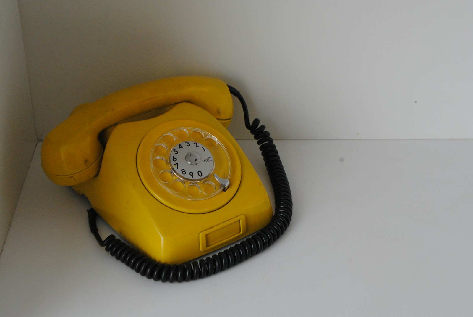 Photo by Marcelo Harassen do Ó A yellow telephone sitting on top of a white counter